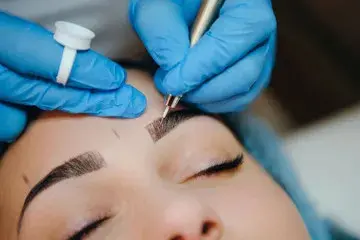 A person getting their eyebrows tattooed